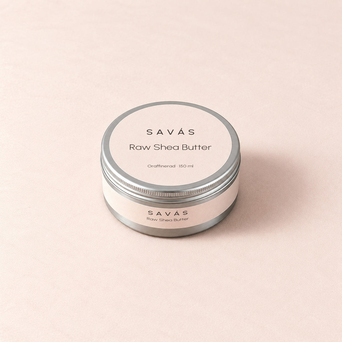 En stängd aluminiumburk med Raw Shea Butter från SAVÁS och etikett på locket, sedd snett ovanifrån