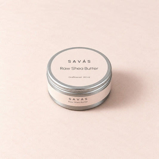 En stängd aluminiumburk med Raw Shea Butter från SAVÁS och etikett på locket, sedd snett ovanifrån
