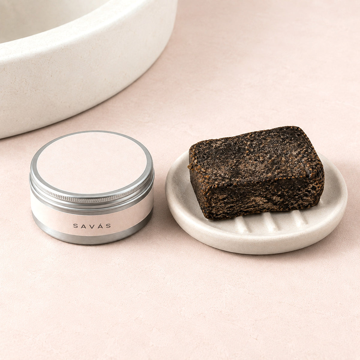 En burk Raw Shea Butter från SAVÁS bredvid en bit svart tvål på ett tvålfat