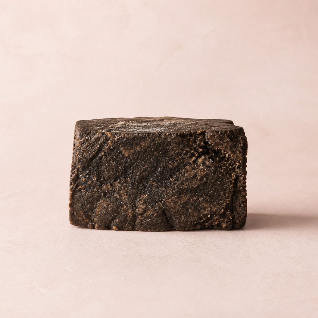 En bit oraffinerad svart tvål på ljus rosa bakgrund